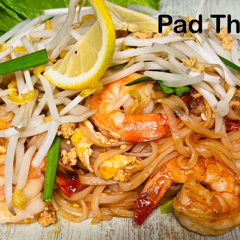 Pad Thai with shrimp, bean sprouts, scallions, and a lemon wedge.